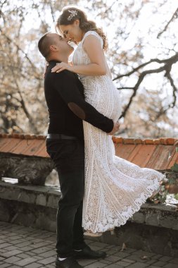 Bir erkek ve bir kadın birbirlerini kucaklıyor, erkek tarafından kaldırılan bir kadın. Sahne muhtemelen bir düğün ya da çift arasında özel bir an. Sahne neşeli ve romantik.