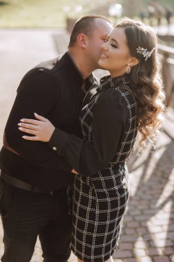 Siyah elbiseli ve beyaz bantlı bir kadınla bir kadın birbirlerine sarılıyorlar.