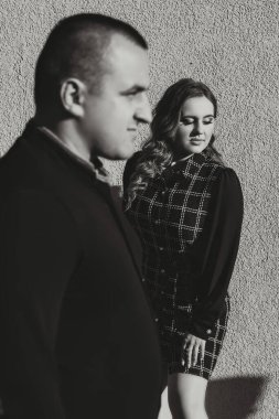 Bir adam ve bir kadın yan yana duruyorlar, her ikisi de siyah giyinmiş. İkisi de gülümsüyor ve kameraya bakıyor.