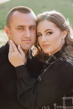 Siyah beyaz bir fotoğrafta bir erkek ve bir kadın birbirlerine sarılıyorlar. Adam sol elinde bir yüzük takıyor. Fotoğrafın sıcak ve samimi bir havası var.