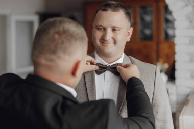 Bir adam kravatını başka bir adama bağlıyor.