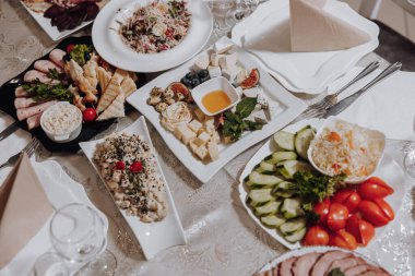 Bir tabak salata, bir tabak salatalık ve bir tabak domates de dahil olmak üzere çeşitli yiyecekler içeren bir masa.