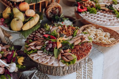 Bir masa et, meyve ve sebze dahil olmak üzere çeşitli yiyeceklerle kaplıdır. Masa bir parti ya da toplantı için hazırlandı ve yemekler görsel olarak çekici ve davetkar bir şekilde düzenlendi.