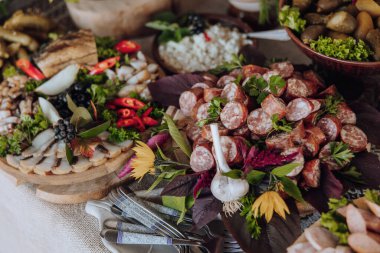 Bir masa et, sebze ve ekmek de dahil olmak üzere çeşitli yiyeceklerle kaplıdır. Masa büyük bir toplantı için hazırlandı ve yemekler görsel olarak çekici ve davetkar bir şekilde düzenlendi.