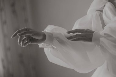 Bir kadının eli siyah ve beyaz bir fotoğrafta gösterilir, kolu uzatılmış ve parmakları açıktır. Zarafet ve zarafet kavramı, çünkü kadın beyaz bir elbise giyiyor.