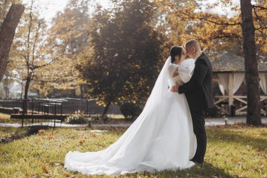 Gelin ve damat çimenli bir tarlada, gelin beyaz bir elbise ve damat siyah bir takım elbise giyiyor. Birbirlerine sarılıp öpüşüyorlar. Sahne çok romantik.