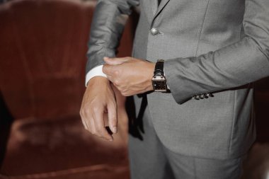 Takım elbiseli bir adam saatini ayarlıyor. Formalite kavramı ve detaylara dikkat