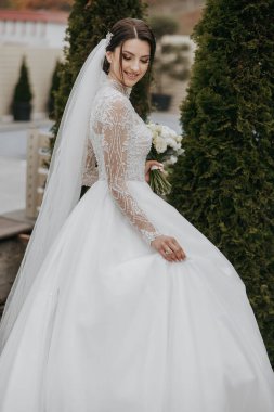 Beyaz gelinlikli bir gelin bir buket çiçekle poz veriyor. Mutluluk ve kutlama kavramı, gelin gelinliğini giymiş ve elinde güzel bir buket tutuyor.