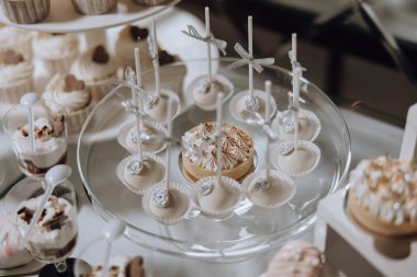 Kekler ve kurabiyeler de dahil olmak üzere çeşitli tatlılar içeren cam bir tepsi bir masada sergileniyor.