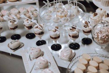 Tatlı ve içeceklerle dolu bir masa. Kekler, kekler ve hamur işleri dahil. Masa bir parti ya da toplanma için hazırlanır ve tatlılar çeşitli cam bardaklar ve kaseler gibi çeşitli şekillerde düzenlenir.