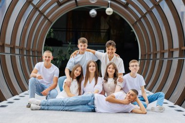 Bir grup genç, bir tünelde fotoğraf çektirmek için poz veriyor. Sahne neşeli ve eğlenceli, çünkü grup birbiriyle rahat ve anın tadını çıkarıyor.