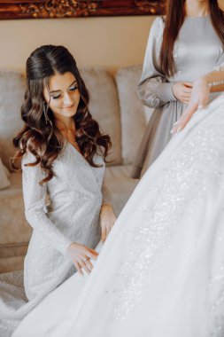 Bir kadın düğüne hazırlanıyor ve elbisesine bakıyor.