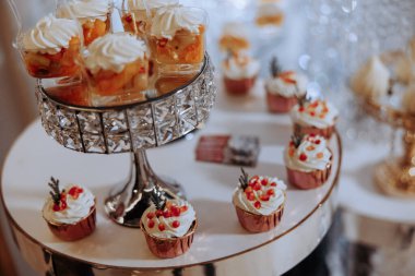 İçinde bir sürü kek ve diğer tatlılar bulunan gümüş tabaklı bir masa. Tatlılar onları çekici ve davetkar gösterecek şekilde düzenlenmiş.