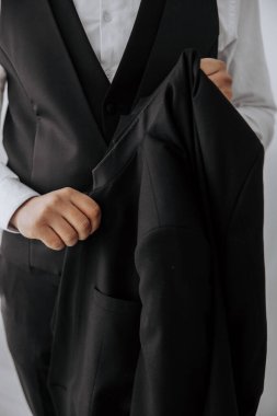 Siyah takım elbiseli bir adam cebini göstermek için ceketi açık tutuyor.