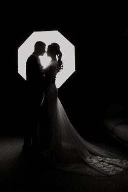 Bir çift ışıklı bir şemsiye önünde öpüşüyor. Görüntü siyah ve beyaz. Sahne romantik ve samimi.
