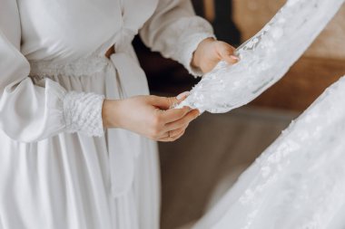 Bir kadın dantel bir elbise tutuyor ve ona bakıyor.