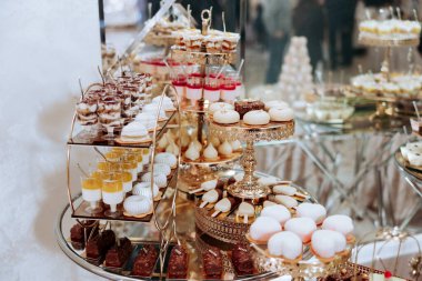 Pastalar, çörekler ve hamur işleriyle dolu bir masa. Tatlılar gümüş tepside sergileniyor ve onları lezzetli ve cezbedici gösterecek şekilde sergileniyor.