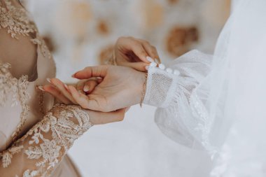 İki kadın düğün için hazırlanıyor. Bir kadın diğer kadının parmağına yüzük takıyor.