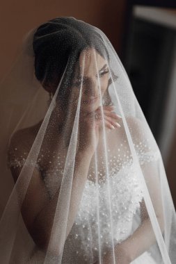 Bir kadın yüzünü örten bir peçe takıyor. O bir aynanın önünde duruyor.