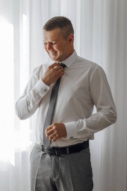 Bir adam kravatını bağlamaya hazırlanıyor. Gülümsüyor ve keyfi yerinde.