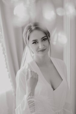 Beyaz bir bornoz giyen bir kadın gülümsüyor. O bir resim için poz veriyor. Fotoğraf siyah beyaz.