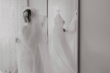 Gelinlik giymiş bir kadın aynanın önünde durmuş peçesini düzeltiyor. Resmin nostaljik ve romantik bir havası var. Özel bir olaya hazırlandığı anı yakalıyor.