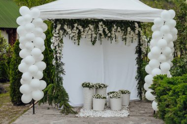 Bahçede beyaz balonları ve çiçekleri olan beyaz bir çadır kurulur. Balonlar bir kutlama ve şenlik havası yaratacak şekilde dizildi.
