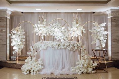 Beyaz çiçekler ve pastayla süslenmiş güzel bir masa. Masa özel bir durum için hazırlandı ve çiçekler ve pasta sahneye biraz zarafet ve şenlik katıyor.