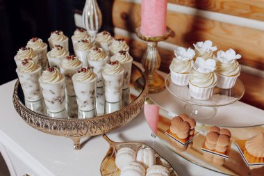 Kekler ve hamur işleri de dahil olmak üzere çeşitli tatlıların olduğu bir masa. Tatlılar gümüş tepside ve beyaz bir masada düzenlenir.