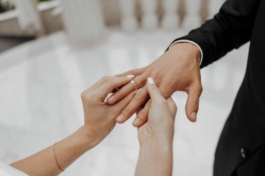 Bir erkek ve bir kadın evleniyor ve erkek kadının parmağına yüzük takıyor.