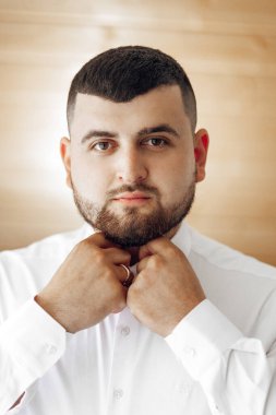 Sakallı ve parmağında yüzük olan bir adam kravatını bağlamaya hazırlanıyor. Görüntü bulanık bir kaliteye sahip, ona biraz sanatsal ya da soyut bir his veriyor. Adamın yüz ifadesi.