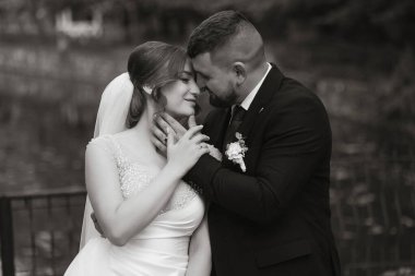 Bir gelin ve damat siyah beyaz bir fotoğrafta birbirlerine sarılıyorlar. Fotoğrafın romantik ve samimi bir havası var.