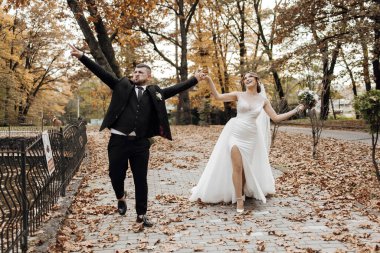 Bir adam ve bir kadın, kadının elini tutan adamla parkta bir patikada yürüyorlar. Kadın beyaz bir elbise ve duvak takıyor. Sahne mutlu ve romantik.