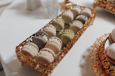 Altın çerçeveli bir tepsi hamur işi. Hamur işleri çeşitlidir ve çeşitli aromalar ve dokular içerir. Tepsi masanın üzerine konur.