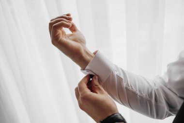 Bir adam giyiniyor ve gömleğini düzeltiyor. Adam gömleğini dikkatlice düzeltirken, rutin ve düzenli olma kavramı