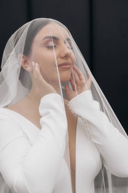 Bir kadın peçe takıyor ve kameraya bakıyor. Duvak bir ağ malzemesinden yapılmış ve yüzünü kaplıyor. Gizem ve entrika kavramı. Kadının yüzü gözlerden uzak.