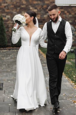 Gelin ve damat bir patikada yürüyorlar, gelin bir buket çiçek tutuyor.