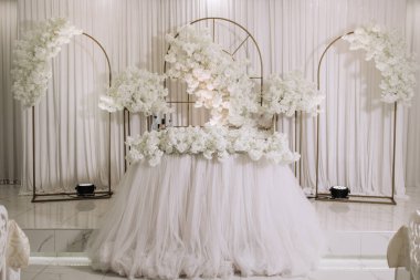 Beyaz çiçekli bir masa ve beyaz bir masa örtüsü. Masa düğün için hazırlandı.