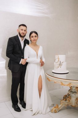 Bir adam ve bir kadın üzerinde H harfi olan bir pastanın önünde poz veriyorlar.