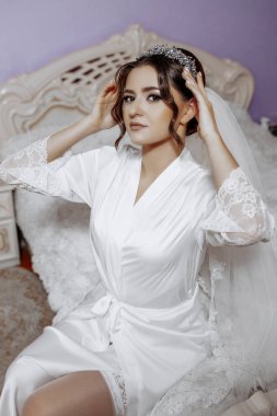 Beyaz cüppeli bir kadın kafasında bir peçeyle bir yatakta oturuyor. O bir taç takıyor ve saçları topuz şeklinde. Zarafet ve incelik kavramı