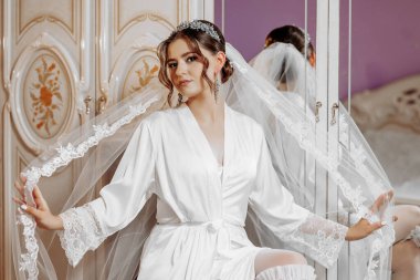 Beyaz cüppeli bir kadın yüzünde bir peçe tutuyor. Zarafet ve resmiyet kavramı, çünkü kadın düğün kıyafeti gibi giyinmiş.