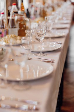 Bir sürü beyaz tabak ve gözlüklü bir masa. Masa akşam yemeği için hazır.