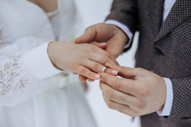 Bir erkek ve bir kadın evleniyor ve erkek kadının parmağına yüzük takıyor.