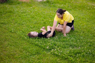 Genç anne ve kızı yeşil çimlerde oynuyorlar ve mutlu bir şekilde gülüyorlar. Kızla çocuk arasındaki karşılıklı anlayış, güven, çocuklarla ilgilenmek, mutlu annelik, bilge anne..