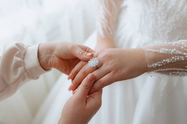 Bir kadın alyans takıyor ve takması için başka bir kadın yardım ediyor. İki kadın arasındaki sevgi ve destek kavramı