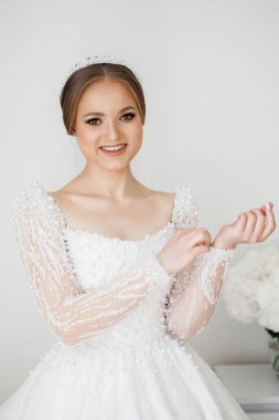 Kafasında taç olan beyaz elbiseli bir kadın. Gülümsüyor ve kameraya bakıyor.