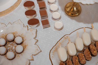 Pasta, kurabiye ve dondurma gibi çeşitli tatlıların olduğu bir masa. Tatlılar tabaklar ve tepsiler üzerine dizilmiştir. Ayrıca biraz da şiş yiyecek vardır.