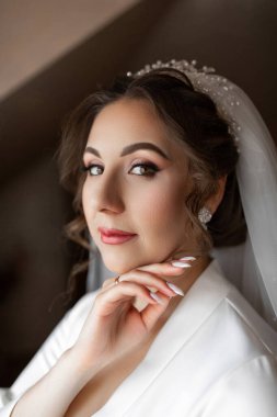 Kafasında duvağı ve beyaz elbisesi olan bir kadın. Parmağında bir yüzük var.