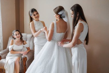 Bir grup kadın düğün için hazırlanıyor. Kadınlardan biri elbisesini düzeltiyor.