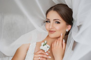 Bir kadın başının üzerinde beyaz bir peçeyle sırt üstü yatıyor ve elinde bir çiçek tutuyor. Yüzünde bir gülümseme var ve gözleri kapalı. Mutluluk ve kutlama kavramı